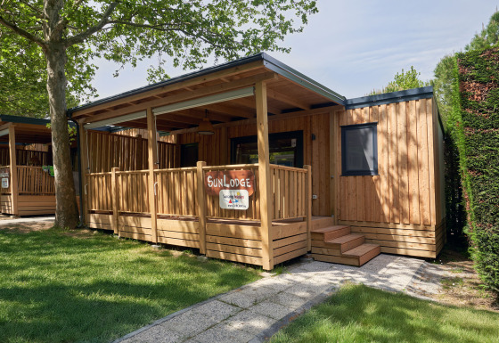 Houten lodge SunLodge Katsura met overdekt terras en groene grasmat in een rustige omgeving.
