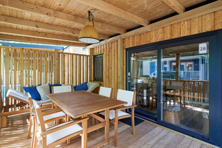 Sunny wooden terrace at SunLodge Katsura featuring a dining table, chairs, and bench with cushions.