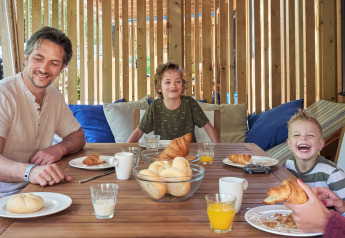 Familia desayunando croissants y zumo de naranja en SunLodge Katsura, hu Park Albatros Village, Italia.