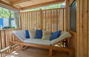 Zona de estar exterior con estructura de madera y cojines en SunLodge Katsura, rodeada de paneles de madera.