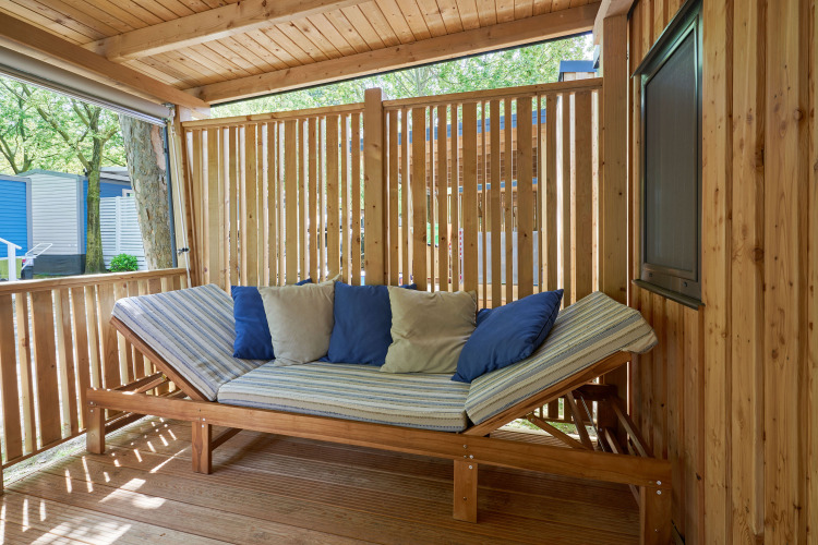 Zona de estar exterior con estructura de madera y cojines en SunLodge Katsura, rodeada de paneles de madera.