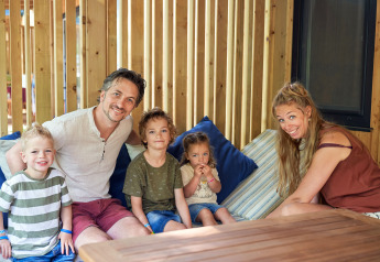 Una familia con tres niños sonríe sentada junta en SunLodge Katsura en hu Park Albatros Village, Italia.