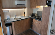 Moderne kitchenette in SunLodge Katsura met houten kasten, spoelbak, gaskookplaat en microgolfoven.