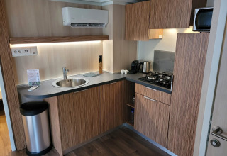 Moderne kitchenette in SunLodge Katsura met houten kasten, spoelbak, gaskookplaat en microgolfoven.