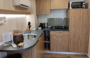 Angolo cottura moderno alla SunLodge Katsura con mobili in legno, fornello a gas, microonde e utensili.