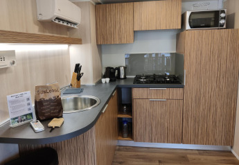 Moderne kitchenette bij SunLodge Katsura met houten kasten, gasvuur, microgolfoven en keukentoestellen.