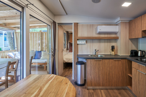 Het interieur van SunLodge Katsura met moderne keuken, eettafel, slaapkamer en een terras buiten.