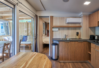 Interieur van SunLodge Katsura met moderne keuken, eettafel, knusse slaapkamer en buitenterras op de achtergrond.