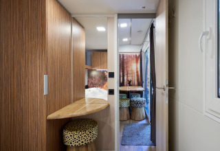 Interieur van SunLodge Katsura met houten afwerking, raam, zithoek en kleurrijke krukken.