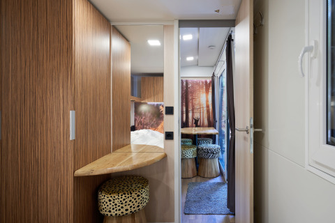 Vista interior de SunLodge Katsura con acabados de madera, ventana y área de asientos colorida.