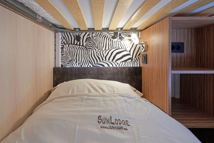 Una cama moderna en SunLodge Katsura en hu Park Albatros Village, Italia, con pared decorada de cebras.