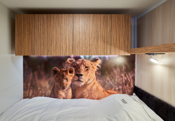 Cama con sábanas blancas y mural de leones en SunLodge Katsura, hu Park Albatros Village, Italia.