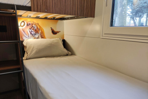 Accogliente stanza alla SunLodge Katsura presso hu Park Albatros Village in Italia con letto singolo e tigre.