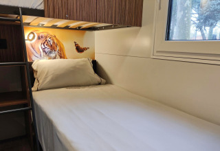 Et hyggeligt værelse i SunLodge Katsura på hu Park Albatros Village i Italien med enkeltseng og tigerbillede.