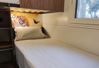 Acogedora habitación en SunLodge Katsura del hu Park Albatros Village en Italia, con cama y arte de tigre.