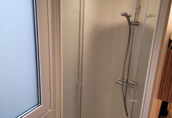 Modern shower cabin with rainfall showerhead next to frosted window at SunLodge Katsura, bright and clean.