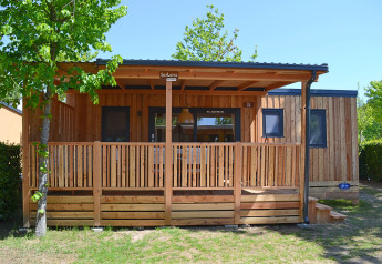 Buitenaanzicht van SunLodge Sabai, een houten lodge met overdekt terras, omgeven door natuur en bomen.