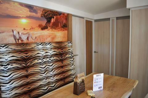 Interni di SunLodge Sabai con murale di ghepardi, panca zebrata e tavolo in legno naturale.