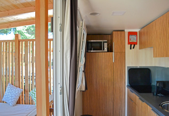 SunLodge Sabai interior with wood cabinets, microwave, small kitchen, and a cozy patio with cushions.