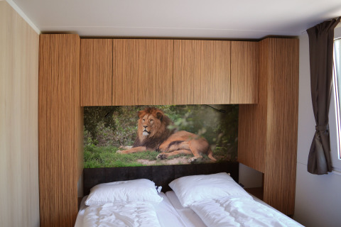 Dormitorio moderno en SunLodge Sabai con dos camas, armarios de madera y mural de león en la pared.