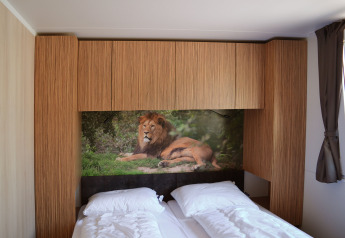 Dormitorio moderno en SunLodge Sabai con dos camas, armarios de madera y mural de león en la pared.