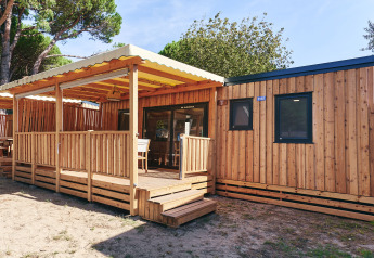 Zonnig zicht op de houten SunLodge Sabai met overdekt terras, moderne ramen en comfortabele zithoek.