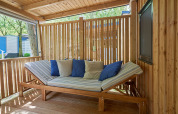 Outdoor lounge with wooden furniture and cushions at SunLodge Katsura, Camping Bella Italia, Italy.