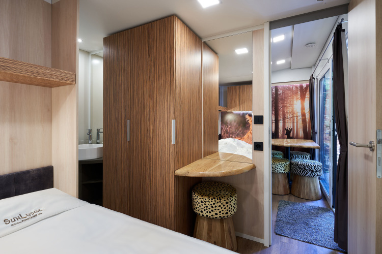 Modern interior of SunLodge Katsura at Camping Bella Italia with wood accents, cozy bed, and animal print stools.