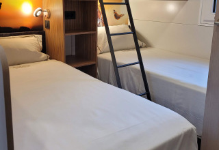 Chambre à SunLodge Katsura avec un lit superposé, deux lits simples, mobilier en bois moderne et draps blancs.