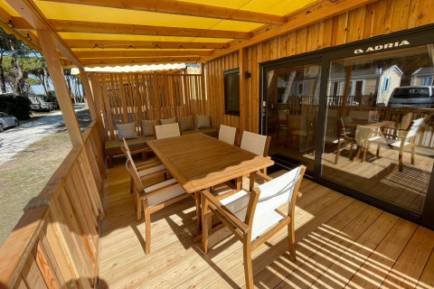 Terrazza in legno soleggiata con tavolo da pranzo alla SunLodge Babul, Camping Union Lido Mare, Italia.