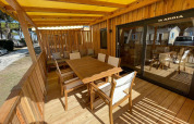 Terrazza in legno soleggiata con tavolo da pranzo alla SunLodge Babul, Camping Union Lido Mare, Italia.