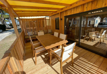 Terrazza in legno soleggiata con tavolo da pranzo alla SunLodge Babul, Camping Union Lido Mare, Italia.