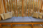 Outdoor wooden bench with grey cushions and patterned pillows at SunLodge Babul, with wooden slats.