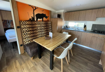 Cucina moderna e zona pranzo al SunLodge Babul con decori animalier e murale di savana sullo sfondo.