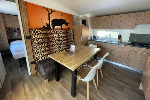 Cocina moderna y comedor en SunLodge Babul, con decoración de estampado animal y mural de sabana al fondo.