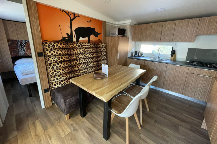 Cocina moderna y comedor en SunLodge Babul, con decoración de estampado animal y mural de sabana al fondo.