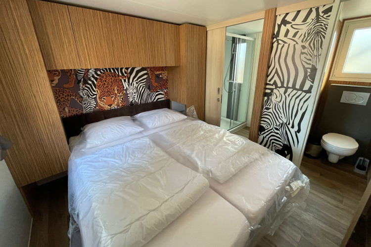 Dormitorio de SunLodge Babul con cama doble, armarios, estampados de animales y baño privado visible.