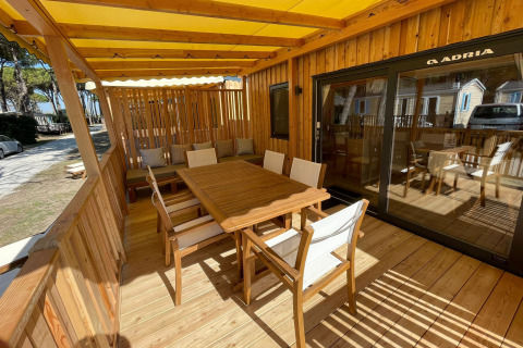 Terrasse en bois ensoleillée avec mobilier extérieur à SunLodge Babul, Camping Village Marina di Venezia, Italie.