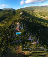 Veduta aerea delle colline intorno a Preci, in Umbria, Italia, con boschi verdi e strade tortuose visibili.