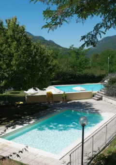 Due piscine circondate da alberi e montagne al Camping Il Collaccio, parco vacanze in Umbria, Italia.