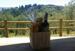 Cesto regalo con vino e snack su un tavolo di legno con vista colline toscane ad Agricamping Romita, Italia.