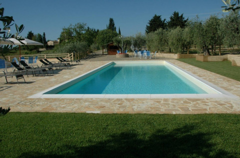 Rectangular swimming pool at Agricamping Romita holiday park in Tuscany, Italy, with loungers and trees.
