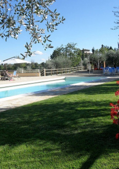 Piscina all’aperto con lettini, ombrelloni e fiori all’Agricamping Romita in Toscana, Italia.