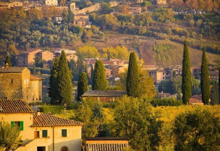 Paysage toscan près de Tavarnelle Val di Pesa avec tours médiévales et vignobles sous la lumière dorée.