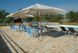 Swimmingpoolområde med parasoller og blå stole på Agricamping Romita feriested i Toscana, Italien.