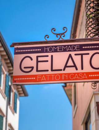 Insegna di gelato artigianale in una via di Tavarnelle Val di Pesa, Toscana, Italia, giornata soleggiata.