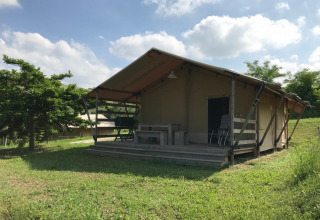 Safari-telt med terrasse i solrigt grønt landskab på Camping Podere sei Poorte feriepark, Marche, Italien.