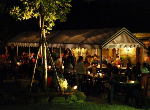 Evening atmosphere at Camping Podere sei Poorte, a holiday park in Marche, Italy, with guests dining outdoors.