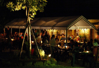 Zomers avondsfeer op Camping Podere sei Poorte, vakantiedomein in Marche, Italië, met etende gasten.