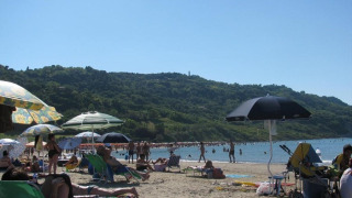Strandzicht bij Camping Podere sei Poorte in Marche, Italië, met zonnende bezoekers en parasols onder groene heuvels.